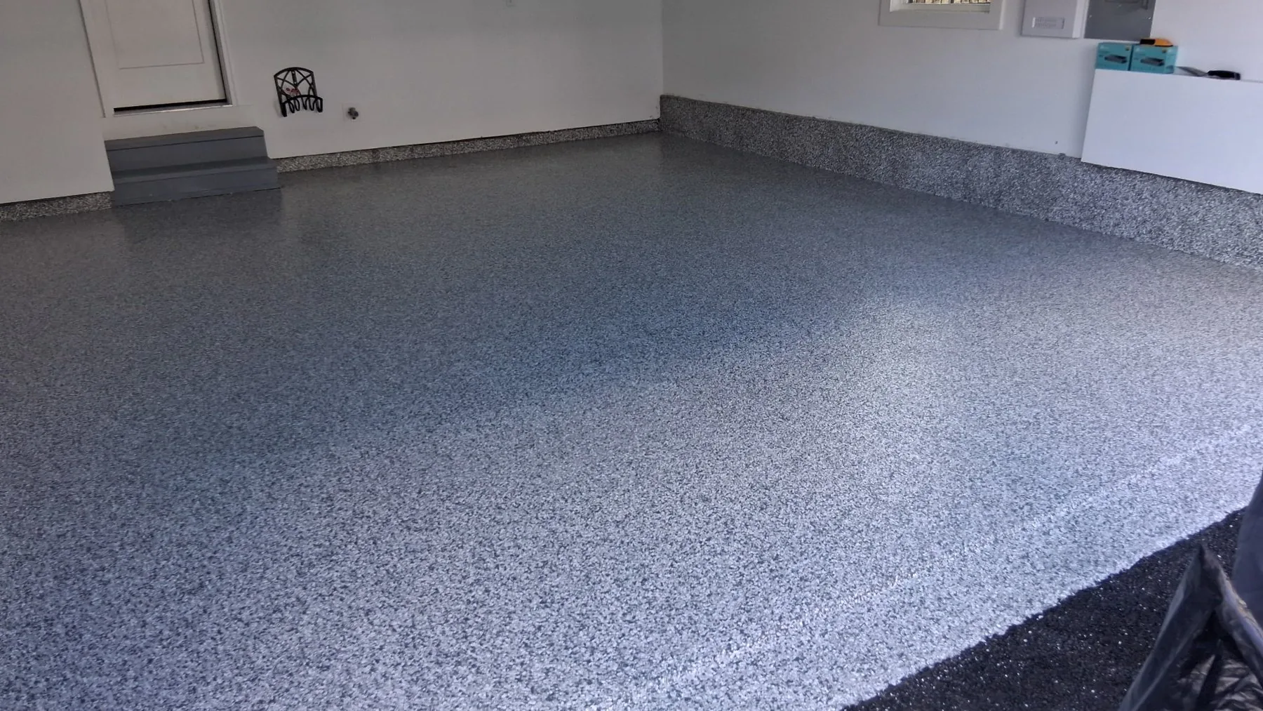 A blue-grey flake garage floor with a step up to the house door