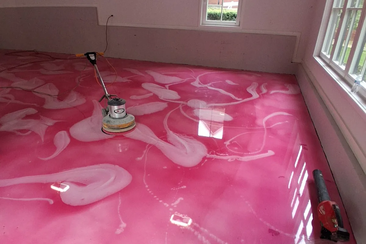 A pink metallic floor being worked with a floor machine