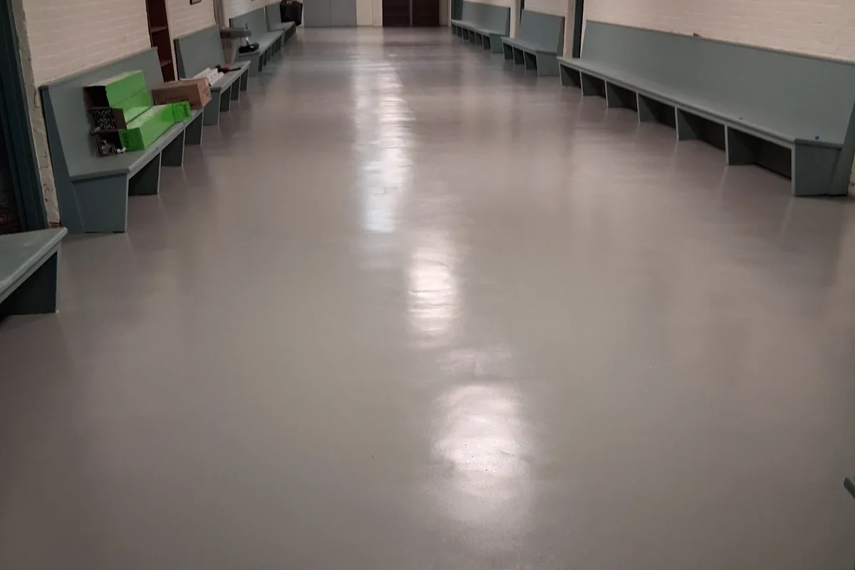 A glossy grey floor down a long room lined with benches