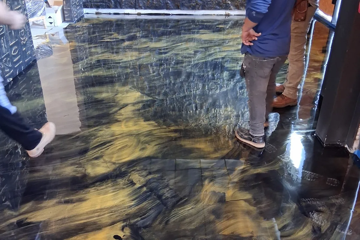 A dark metallic floor with gold veins, with two people standing on it