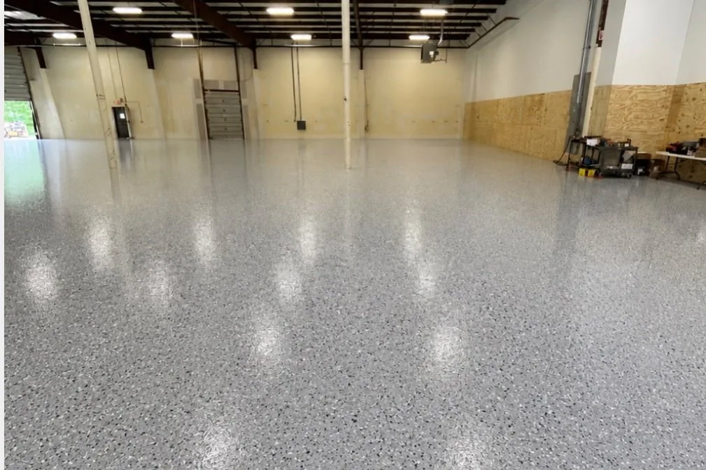 A grey flake floor across a large open workshop with a roller door at the back