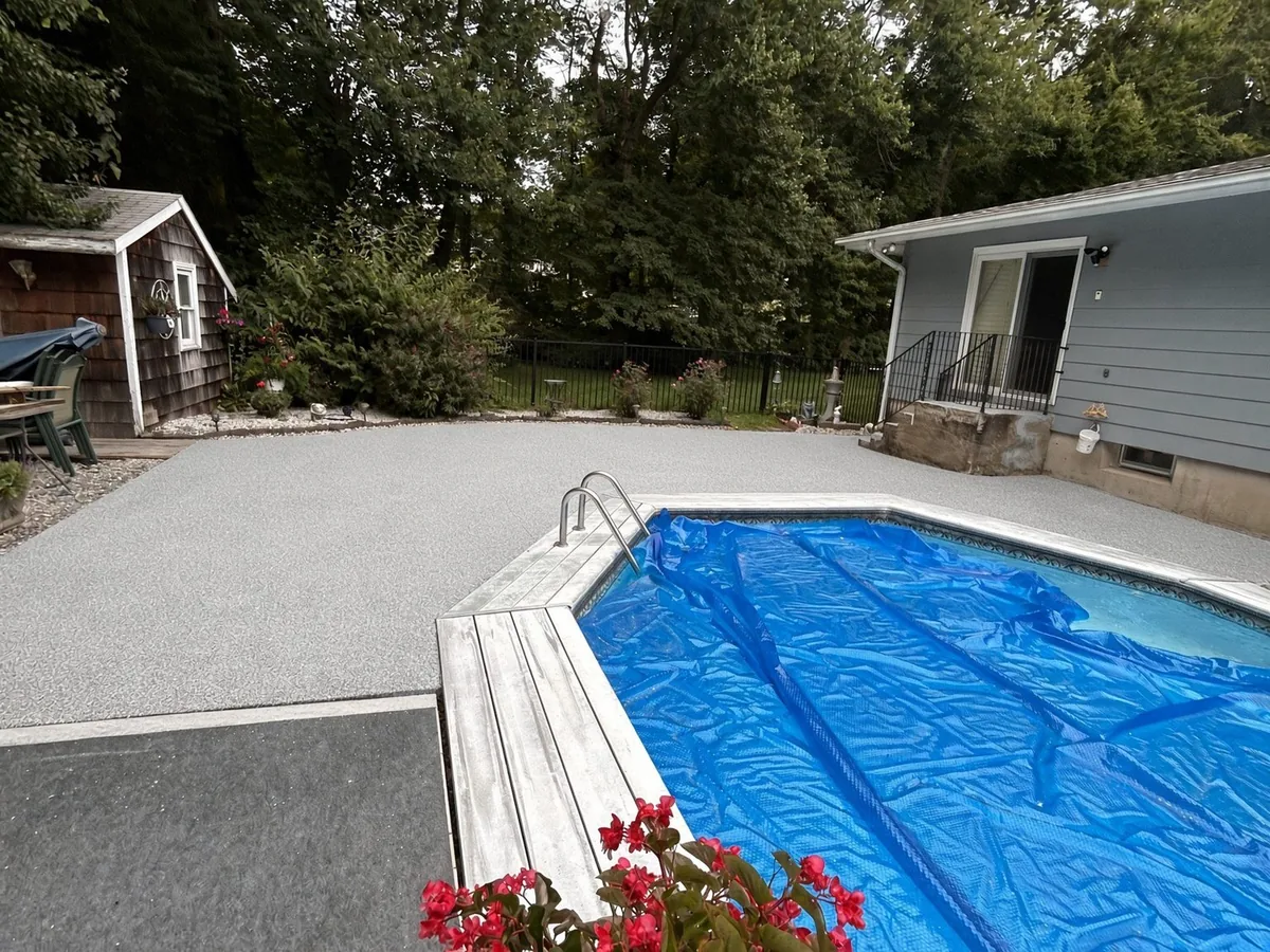 A pale textured coating around an in-ground pool under a blue cover